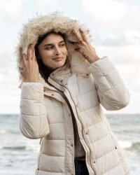 front-view-smiley-woman-beach-with-winter-jacket